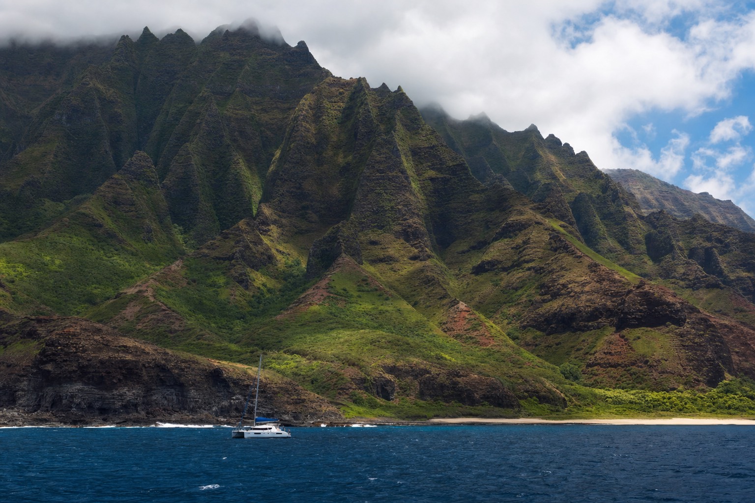 Na Pali Coast cliffs rising from the ocean with a catamaran below