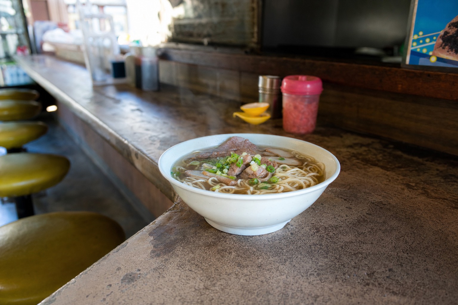 Steaming bowl of saimin noodles on a worn lunch counter in a Kauai plantation town